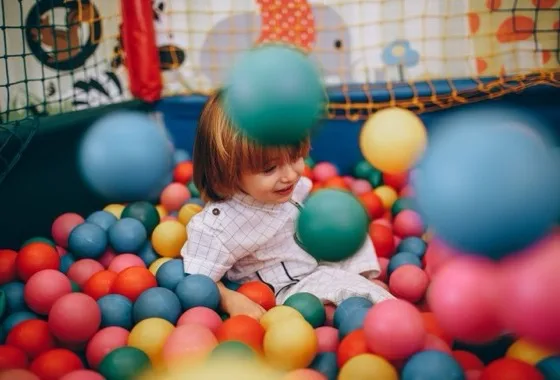 Bambina che gioca nella piscina di palline di una ludoteca