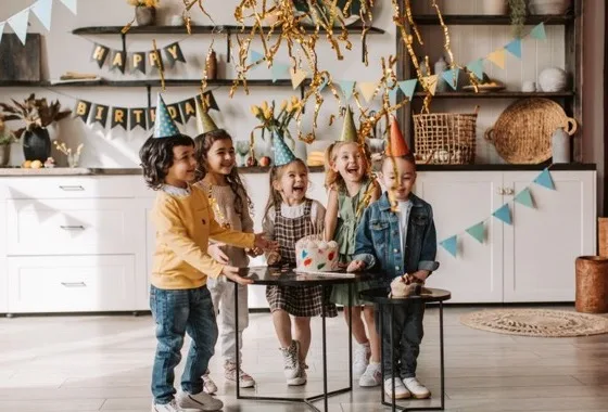 Bambini attorno al tavolo di una festa, con festoni e bandierine