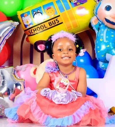 Bambina in abito da festa davanti a un arco di palloncini